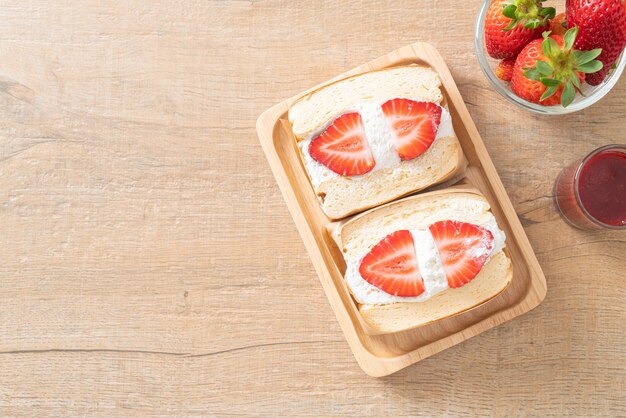 Sándwich de panqueques con crema fresca de fresa sobre placa de madera