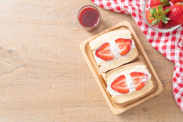 Sándwich de panqueques con crema fresca de fresa sobre placa de madera