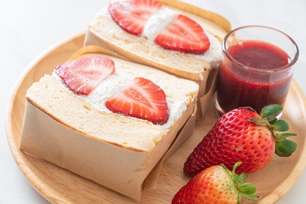 Sándwich de panqueques con crema fresca de fresa sobre placa de madera