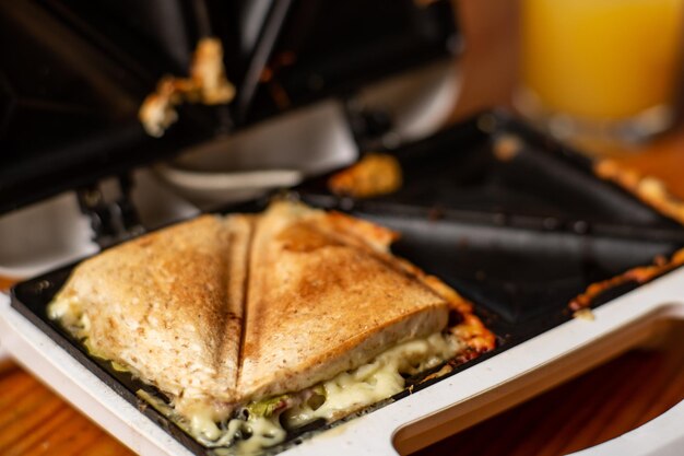 Sándwich a la parrilla con queso y hierbas en una sandwichera Desayuno ligero