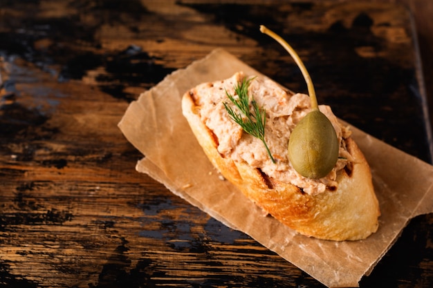 Sándwich de paté de pollo con alcaparras sobre una vieja placa oscura.