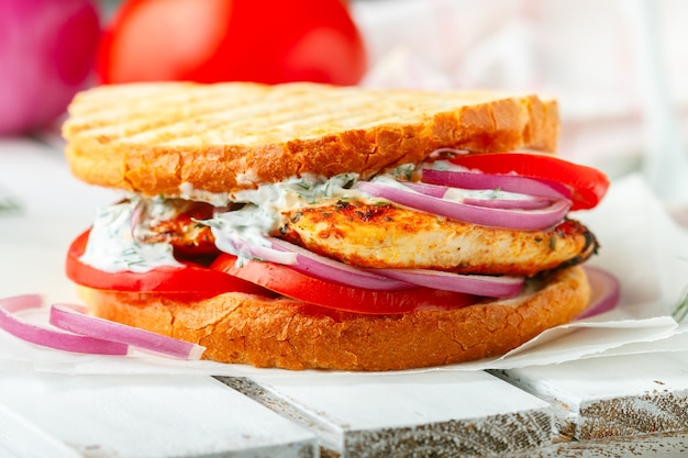 Sandwich con pechuga de pollo frita, tomate, cebolla morada y salsa tzatziki, aperitivo gourmet