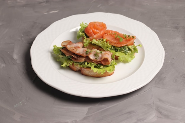 Foto sándwich de pescado rojo en salazón y lechuga y sándwich de bacon frito y lechuga
