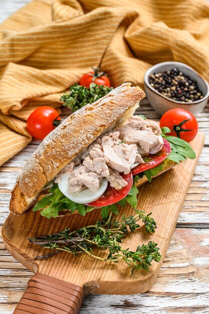 Sándwich de pescado, rúcula, tomate, huevo y hierbas