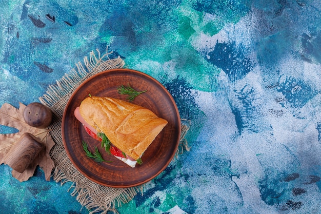 Sándwich en una placa de madera sobre una servilleta de arpillera, en el azul.