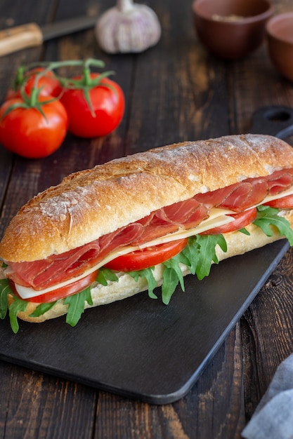 Sándwich de prosciutto, tomate, rúcula y queso. Alimentación saludable. Dieta.