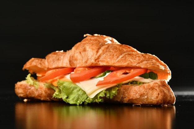 Foto un sándwich con queso, lechuga, tomate y lechuga en una mesa
