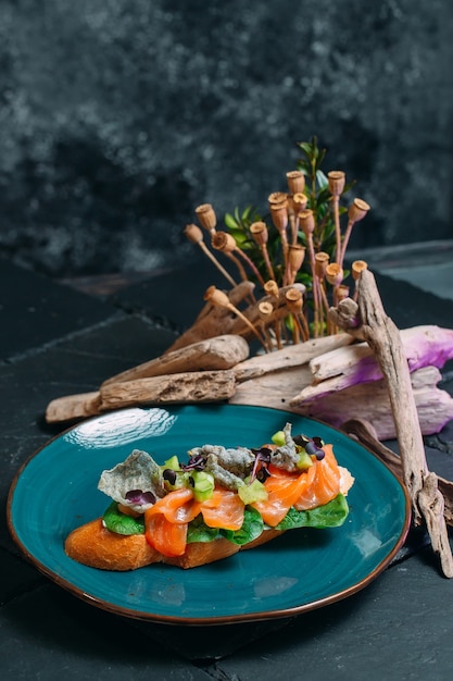 Sándwich con rodajas de delicioso salmón y hierbas sobre un fondo elegante