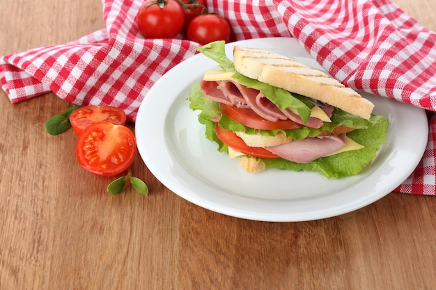 Sándwich sabroso con jamón en mesa de madera