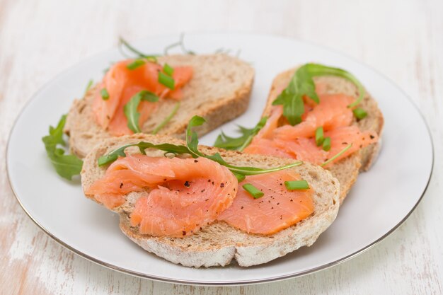 Foto sandwich con salmón ahumado en plato blanco sobre blanco