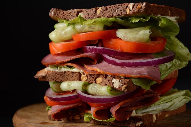 Sándwich de ternera ahumada, cebolla morada, pepino, tomate, lechuga y pan integral. Delicioso almuerzo saludable con carne.