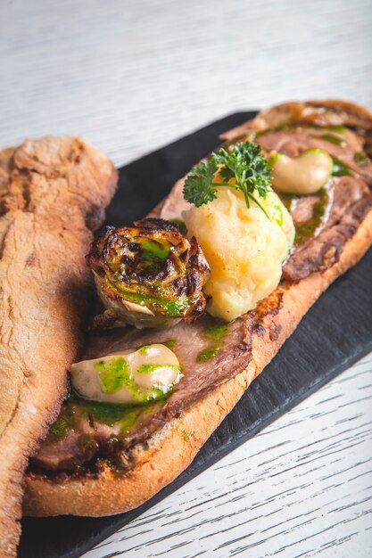 Sándwich de ternera desmenuzada, cebolla crujiente y crema de alcachofas