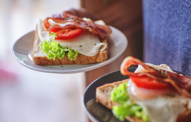 Un sándwich con tocino y tomate encima