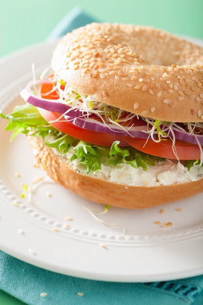 Sandwich de tomate en bagel con queso crema, cebolla y lechuga