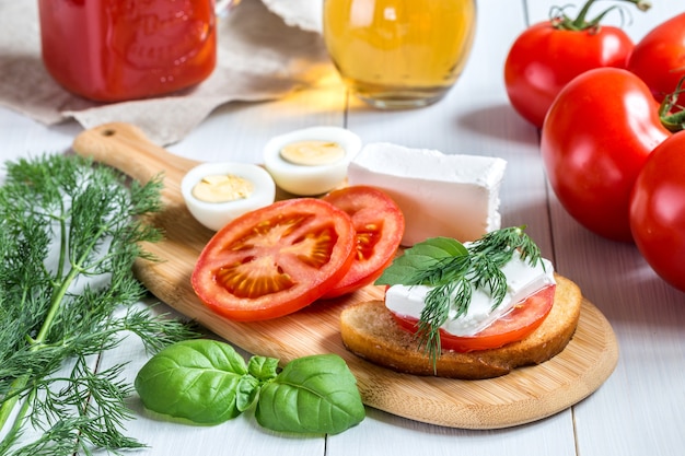 Un sándwich con tomate, queso y hierbas.