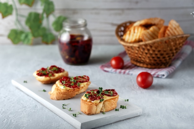 Sándwich con tomates secos y micro verdes en una placa blanca.