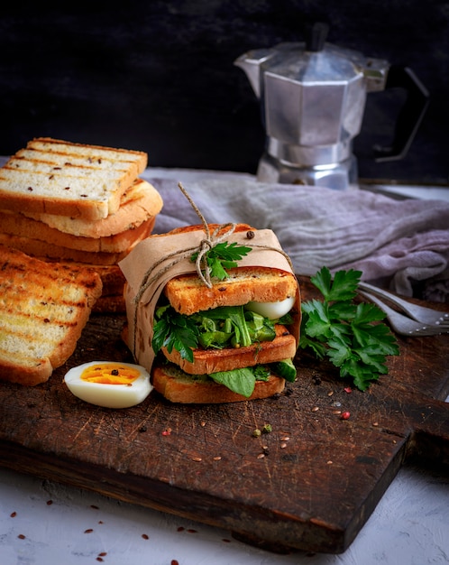 Sándwich de tostadas y hojas de lechuga y huevo cocido.