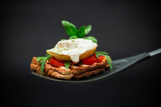 Sándwich de tostadas preparadas con huevo frito con especias y hierbas en una espátula de cocina