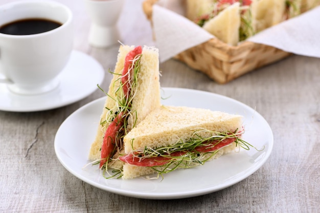 Sándwich de tostadas de trigo con queso crema con microbrotes de cebolla verde y salami. Alimentos saludables y frescos.