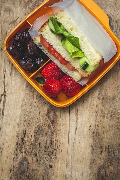 Sandwich vegano en recipiente de plástico sobre mesa de madera. Concepto de comida sana