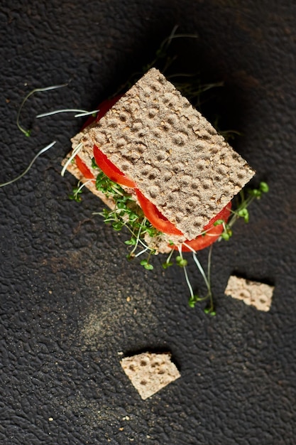Sándwich vegano saludable con tomate de pan de centeno crujiente y microvegetales