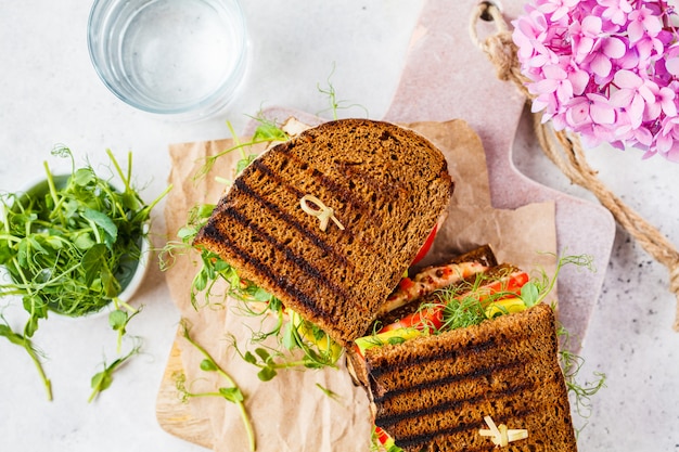 Sandwich vegano con tofu, hummus, aguacate, tomate y brotes.