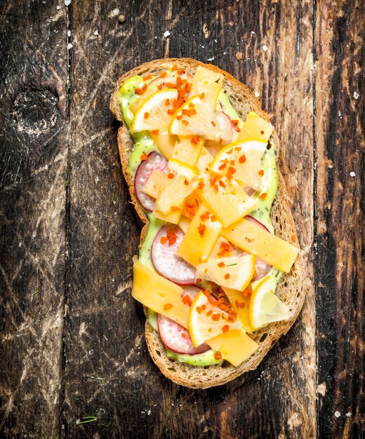 Sándwich vegetariano con queso, rábano y salsa de hierbas frescas en la mesa de madera.