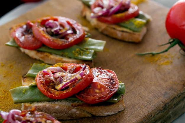 Sandwich de verano preparado con cebolla roja frita, tomate y frijoles