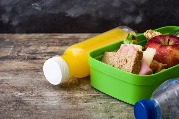 Sandwich, verduras y frutas en mesa de madera