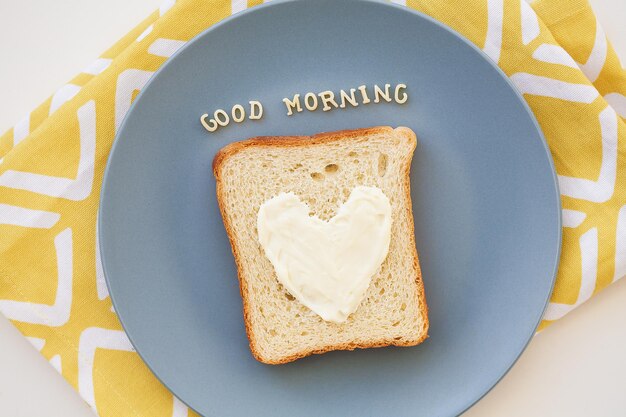 Sandwich zum Frühstück in Herzform mit Blauschimmelkäse auf einem Teller und Serviette helle Aufschrift guten Morgen