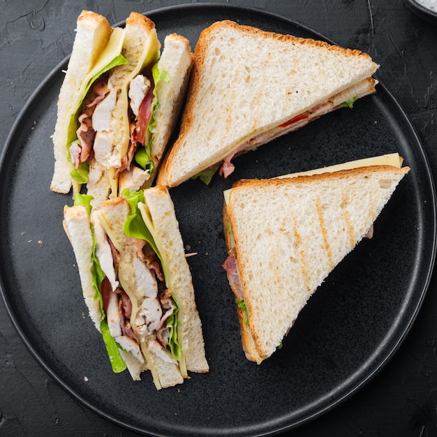 Sandwichbrot Tomate, Salat und gelber Käse, auf schwarzem Hintergrund, Draufsicht