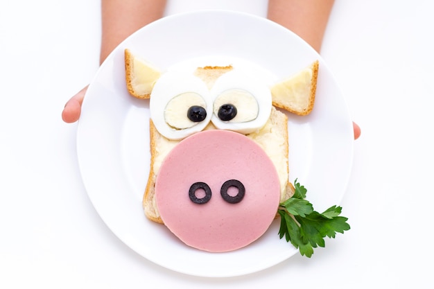 Sandwichbulle. Kinderhände haben einen weißen Teller mit einem Sandwich zum Frühstück oder Mittagessen.