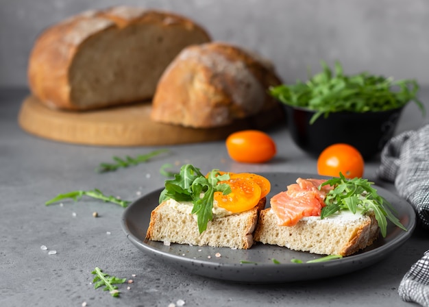 Sándwiches abiertos con pan de trigo y centeno, tomates, salmón ahumado y rúcula.