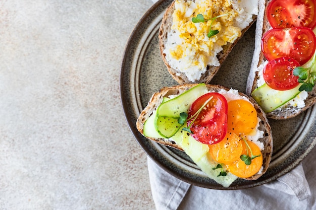 Sándwiches abiertos con pepino, tomate, queso crema y huevo revuelto