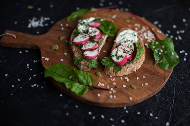 Foto sándwiches abiertos sobre pan de centeno oscuro con huevos, camarones, rábanos, pepino y queso crema.