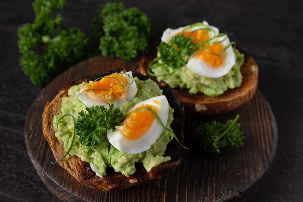 Sándwiches con aguacate y huevo foto oscura enfoque selectivo