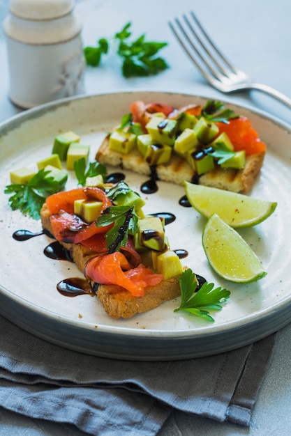 Sándwiches de aguacate y salmón con salsa balsámica y cilantro sobre tabla de olivo viejo