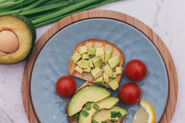 Sándwiches con aguacate, tomate y hierbas sobre un fondo de madera sobre la mesa. concepto de alimentación saludable y vegetarianismo, el desayuno adecuado para una buena digestión.