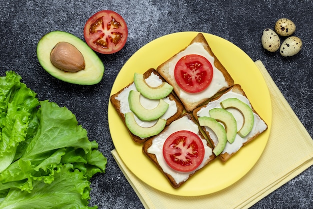 Sándwiches de aguacate y tomate en una placa amarilla