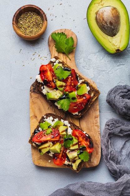 Sándwiches de aguacates, tomates cherry y queso feta con salsa balsámica y cilantro. Vista superior.