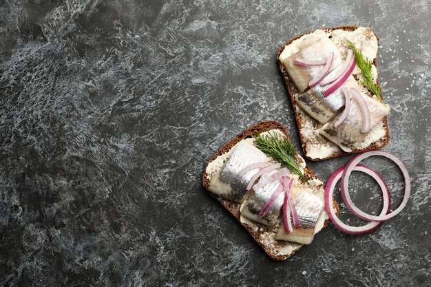 Sándwiches con arenque sobre fondo negro ahumado