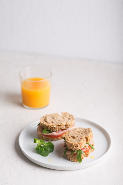 Sandwiches caseros preparados con verduras frescas y aceite de oliva. Desayuno saludable con jugo de naranja.