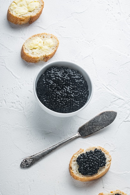 Sándwiches con caviar negro y mantequilla, sobre fondo blanco.
