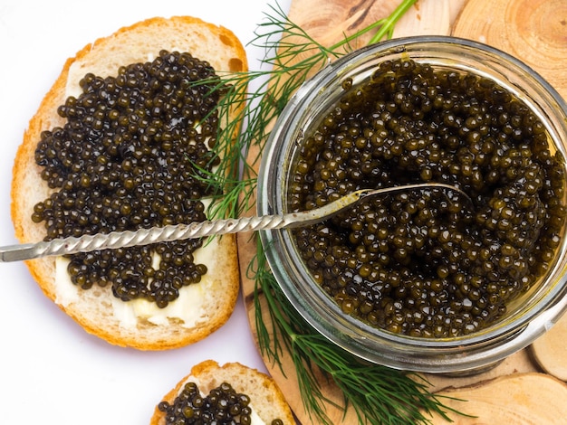 Sándwiches con caviar negro un tarro de caviar y una cuchara