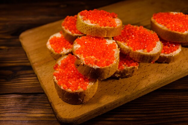 Sándwiches con caviar rojo sobre una tabla para cortar