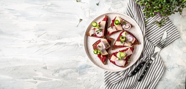 Sándwiches con cebollas de arenque y ensalada de remolacha pepino fresco Tradición Sándwich abierto danés smorrebrod con herrin Formato de banner largo vista superior