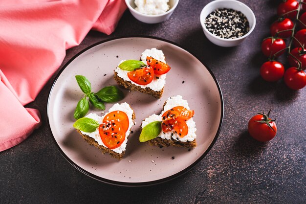 Foto sándwiches de corazón con ricotta y tomates en pan de centeno en un plato