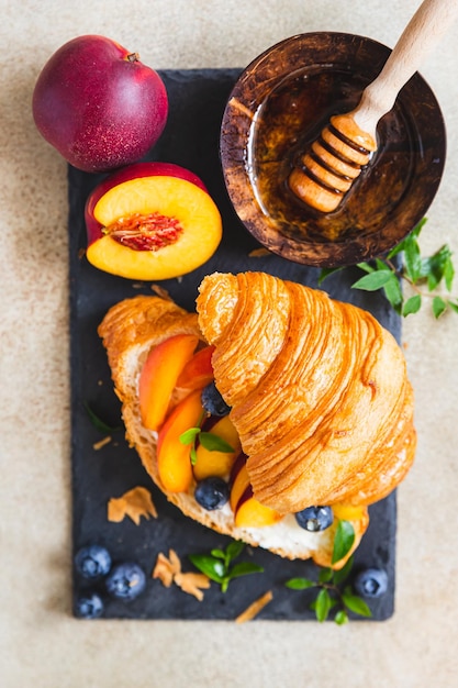 Sándwiches de croissant vegetariano con nectarina suave o queso crema arándanos y miel