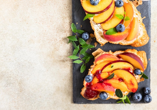 Foto sándwiches de croissant vegetariano con nectarina suave o queso crema arándanos y miel