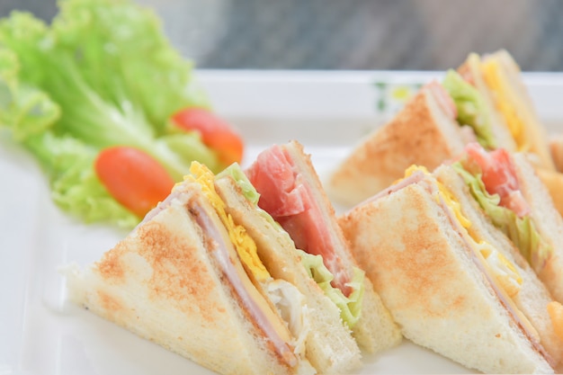 Sándwiches de desayuno con ensalada y tomate en el plato blanco.